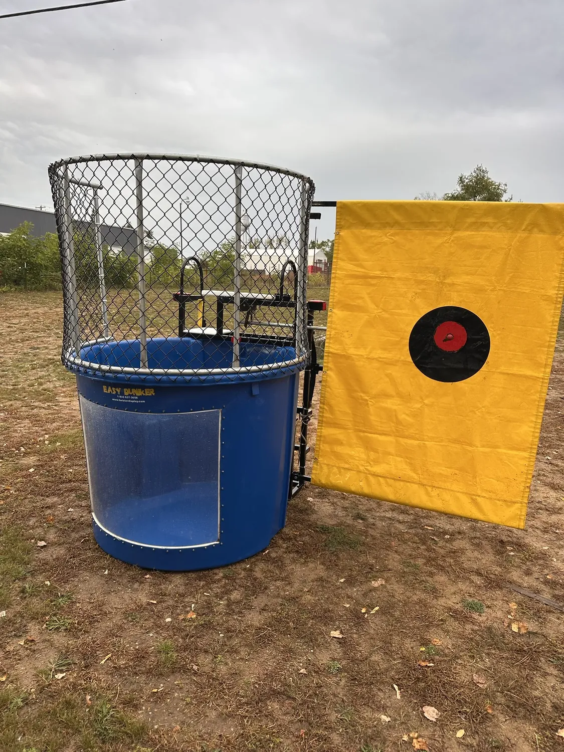 Blue dunk tank with yellow target banner set up in the fenced field for the 2nd Annual Harvest Festival
