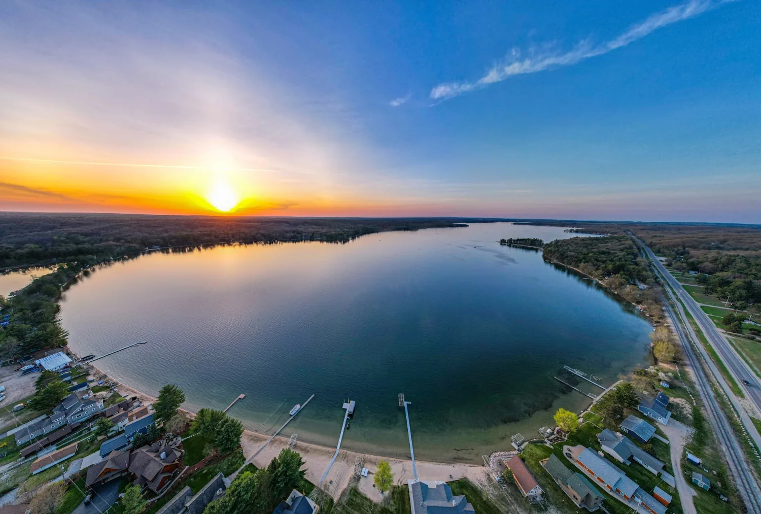 Aerial sunset photo of Otsego Lake showing Old US Hwy 27 S and Trail 27 running along the east shore on the right, across the street from The Lakeside Pavilion